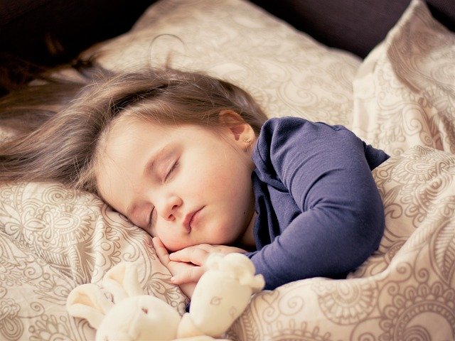 Young girl sleeping in a bed.